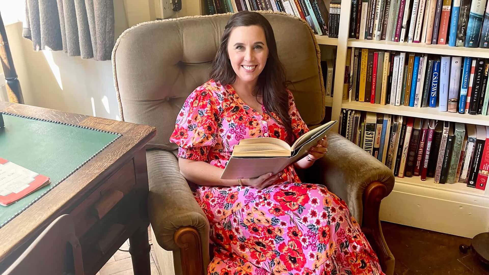 One of the hosts reading in a library armchair