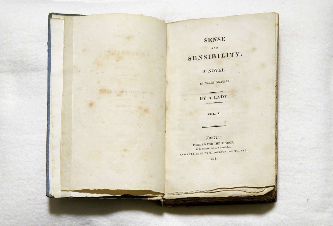 a book open to the title page with the title of "Sense & Sensibility" by a Lady